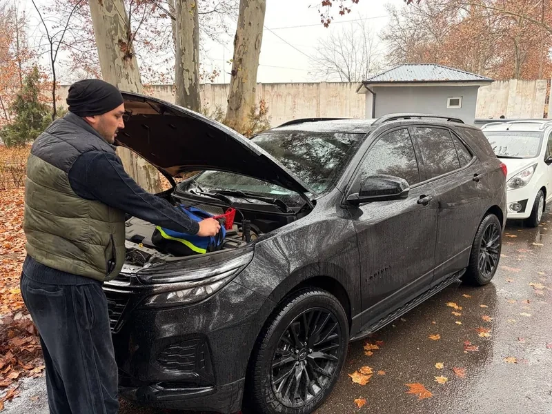Мастер подключает пусковое устройство под капотом Chevrolet Equinox